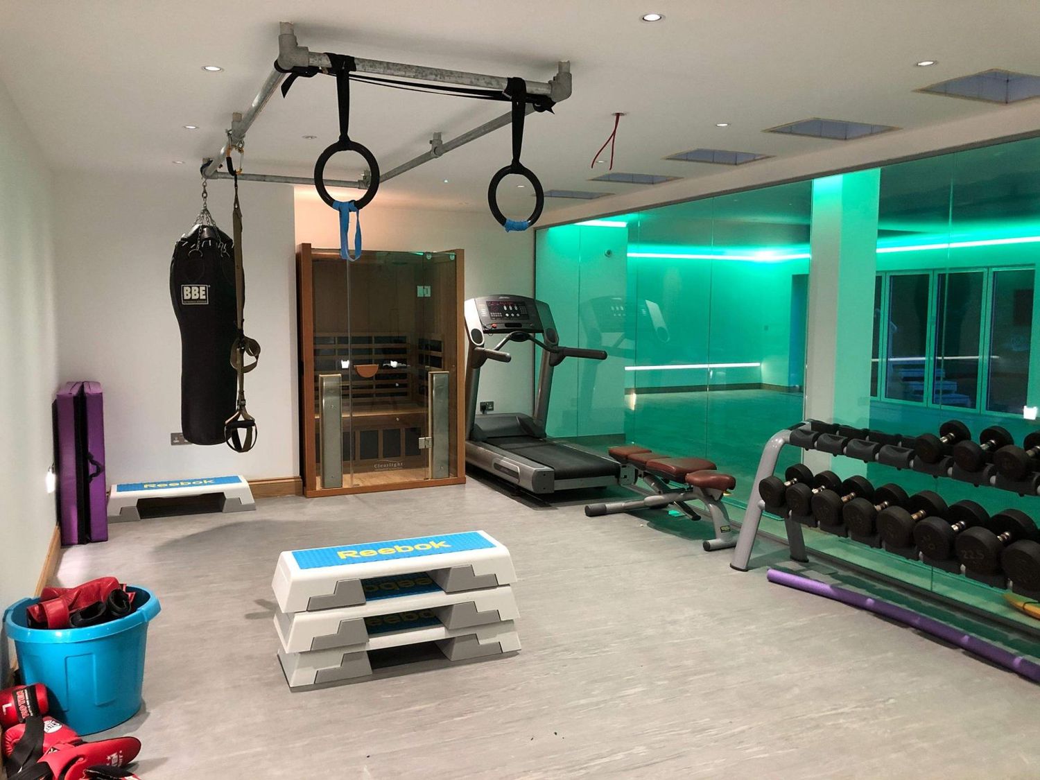 Home gym with LED-lit glass screen onto the pool hall